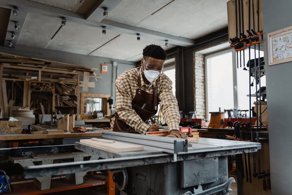 A professional woodworker focused on crafting, wearing safety gear in a workshop.
